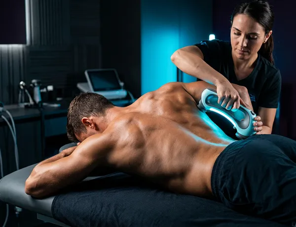 close-up of athlete back muscles undergoing physical therapy with cyan light contrast