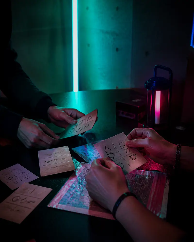 hands decoding cipher cards and notes on dark table